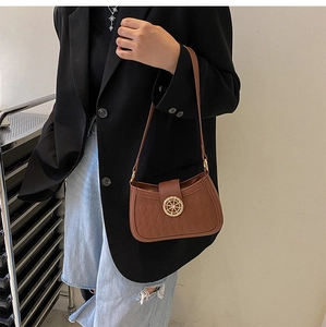 Detail of vintage brown shoulder bag showing quilted texture and gold rudder buckle
