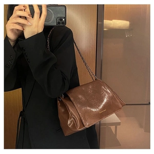 Detail of dark brown leather chain bag with gold logo shown in a lifestyle mirror selfie