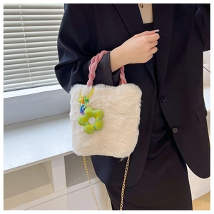 Détail du sac seau en peluche blanche avec poignées roses et pendentif fleur verte
