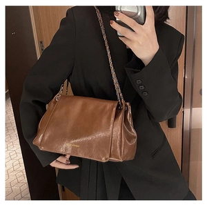 Close-up of vintage brown oil wax leather shoulder bag with golden chain strap and logo