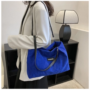 Detail of Klein blue corduroy tote bag featuring leather straps and FASHION logo