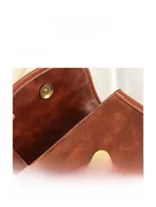 Detail of brown lychee leather bag with white stitching and gold magnetic snap button