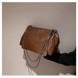 Close-up of caramel glossy leather tote bag with silver chain straps and flap design