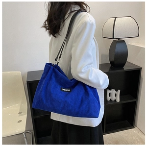 Detailed close-up of corduroy texture and fashion logo on the cobalt blue tote bag