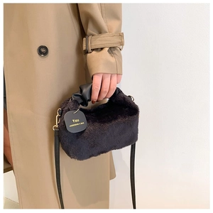 Detail of black faux fur handbag with leather handle and decorative gold-lettered tag
