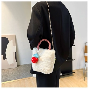 Détail du sac seau en fausse fourrure blanche avec anse rose et breloque fraise