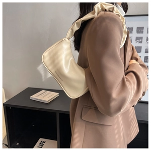 Detail view of beige baguette bag with pleated shoulder strap and logo print