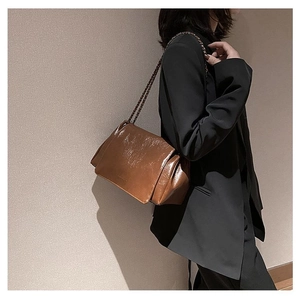 Detail of a brown oil wax leather tote with retro pleated texture and chain strap