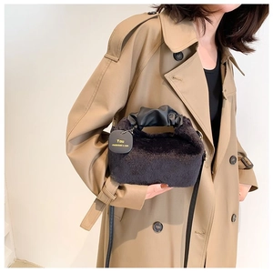 Detail of plush black handbag with pleated leather handle and grey designer tag