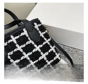 Detailed macro view of black and white tweed fabric and leather stitching on the handbag