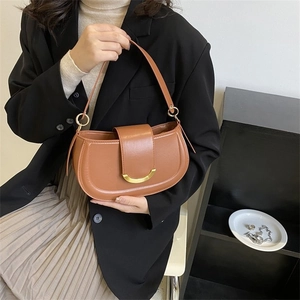 Sacoche marron avec boucle dorée en croissant, portée par un mannequin avec élégance