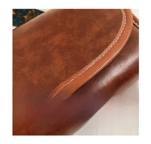 Close-up of contrast stitching on vintage brown faux leather shoulder bag texture