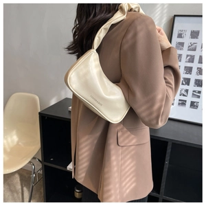 Detail of cream-white leather baguette bag with a stylish scrunchie shoulder strap