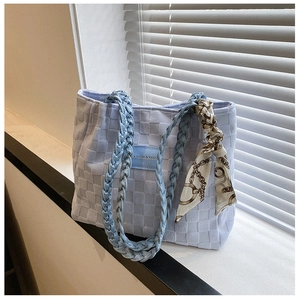 Detail of light blue checkered tote bag with woven handles and silk scarf ornament