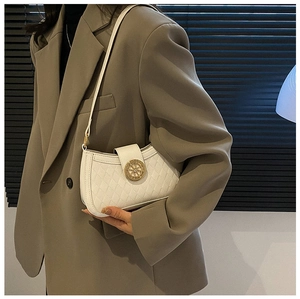 Close-up of white quilted leather shoulder bag with vintage gold circular buckle hardware