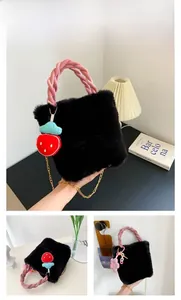 Détail d'un sac seau en peluche noire avec anse tressée rose et charms mignons