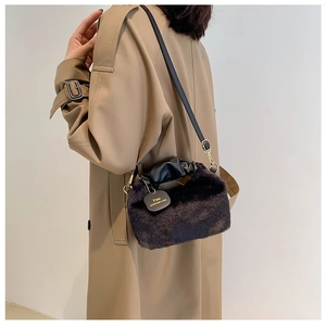 Close-up of brown plush faux fur bag with black leather handle and You decorative tag