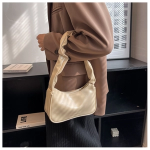 Detail view of cream pleated baguette bag with wide gathered strap and metallic zipper