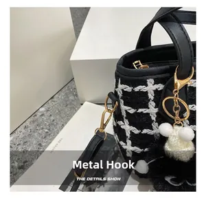 Close-up of gold-tone hardware hook and tweed fabric texture on a bucket bag