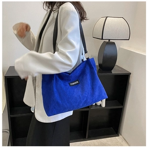 Detail of the blue corduroy tote bag with FASHION label and wide shoulder strap