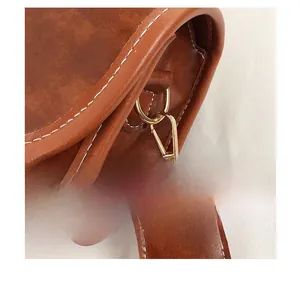 Detail of a brown leather bag with golden metal swivel hooks and white contrast stitching
