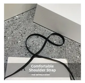 Detail shot of the sleek black adjustable shoulder strap on a textured surface