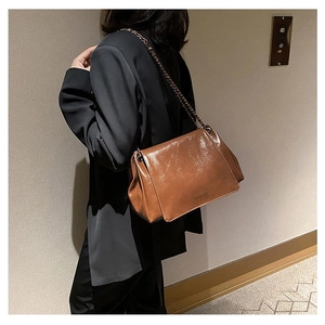 Detail of caramel brown soft leather tote bag with metal chain strap on model