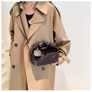 Close-up of black plush crossbody bag with pleated leather handle and long strap