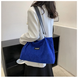 Close-up of Klein blue corduroy tote bag with black shoulder straps and Fashion label