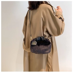 Close-up of fluffy dark brown plush bag with black pleated handle and gold tag details