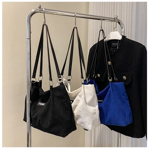 Detail of corduroy tote bags in black, white and blue with Fashion label and metal rings