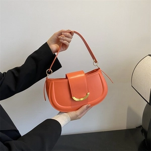 Détail du sac selle orange vif en cuir grainé avec boucle en croissant doré