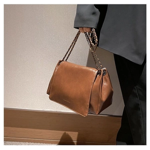 Detail of a dark brown chain shoulder bag featuring accordion side folds and glossy finish