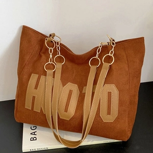 Grand sac cabas en daim marron avec écusson HOJO et bandoulière en chaîne dorée sur livre