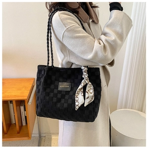 Detail of black checkered tote bag featuring a logo patch and silk scarf accent