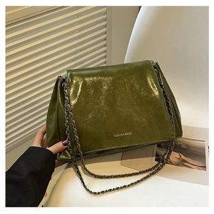 Detail of dark green oily leather tote bag with FASHION BAGS logo and chain strap