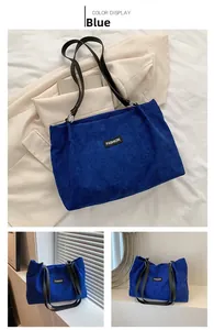 Detail of blue corduroy tote bag featuring leather handles and a fashion fabric label