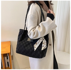 Detail of black woven tote bag with fashion label and gold chain print silk scarf accessory