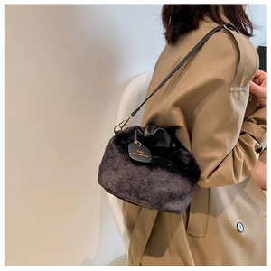 Detail of black plush handbag featuring drawstring closure and gold metal hardware