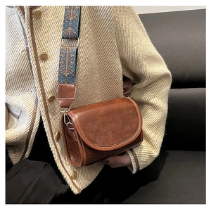 Close-up of vintage brown leather shoulder bag with ethnic patterned wide strap
