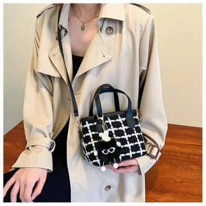 Classic black and white tweed bucket bag with adorable plush charm on beige coat
