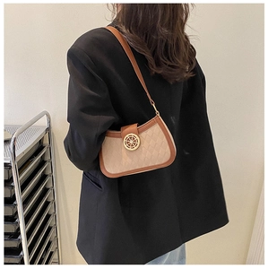 Detail of quilted beige crossbody bag with vintage gold hardware on model in black blazer