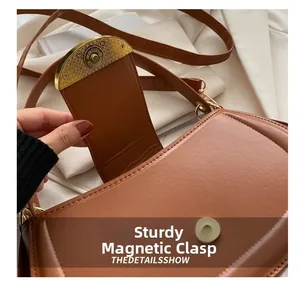 Vue détaillée du fermoir magnétique en métal sur un sac besace vintage en cuir marron
