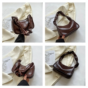 Detailed close-up of dark brown pleated handle and glossy leather finish on underarm bag