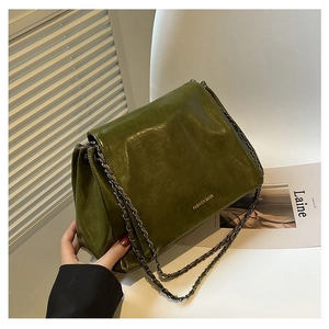 Detail of vintage green faux leather tote bag featuring fashion text and chain strap