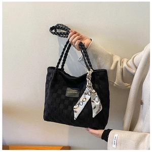 Detail of black woven tote bag with diamond pattern and geometric print silk scarf