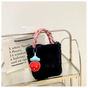 Détail du sac seau en fausse fourrure noire avec anse tressée en velours rose et breloque