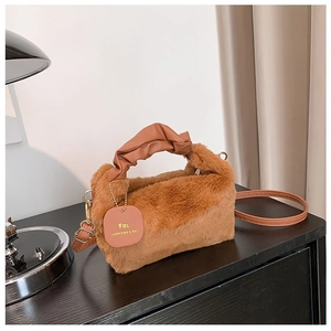 Close-up of caramel plush handbag featuring ruffled leather handle and brand tag