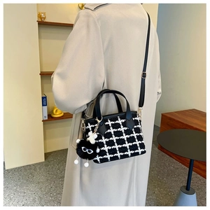 Fashionable black and white checkered tweed bucket bag shown on a model's shoulder