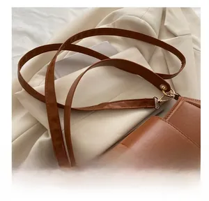 Détails du sac besace vintage en cuir marron avec boucle dorée et large bandoulière